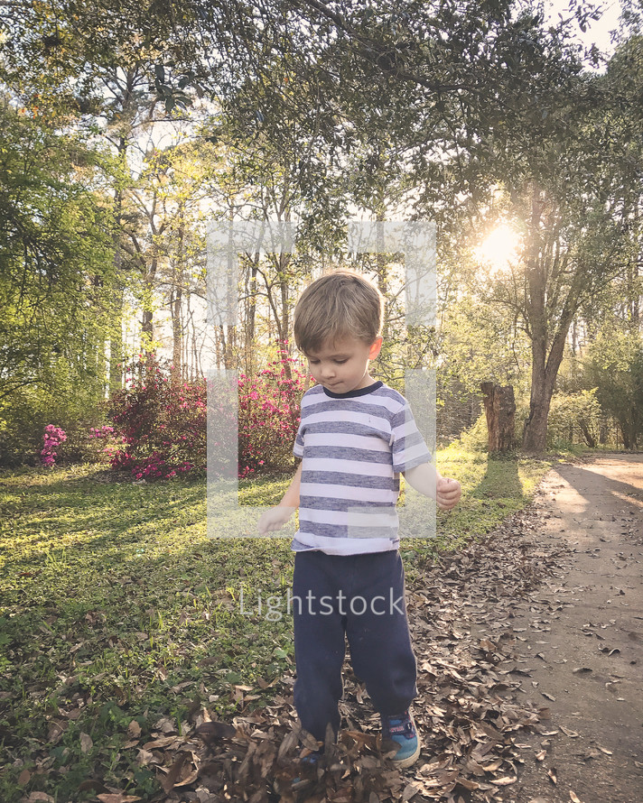 a boy walking on a sidewalk in a neighborhood in spring 