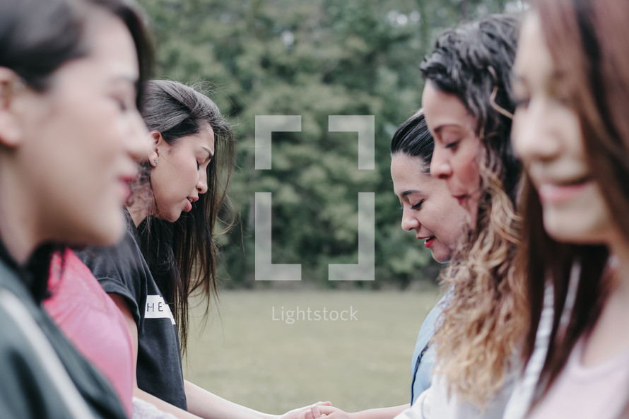  young women holding hands in prayer 