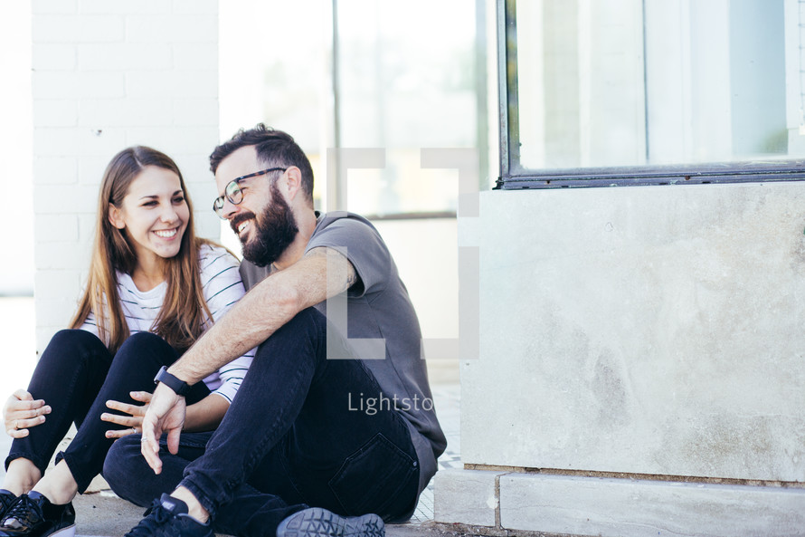 couple sitting on a sidewalk 