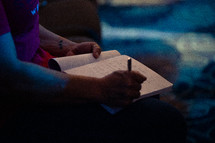 a man writing in a journal during a worship service 