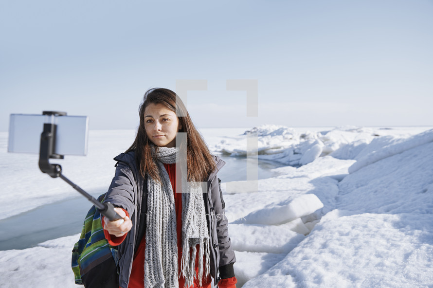 a young woman taking a selfie standing outdoors in snow 