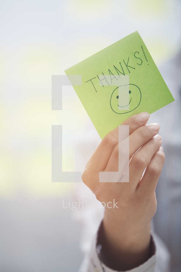 a woman holding a sticky note with the words thanks 