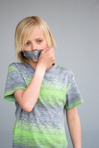 a boy child with duct tape over his mouth 