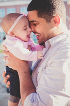 Father and infant daughter laughing together.