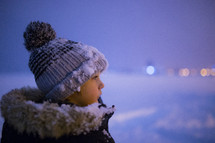 a child in a beanie in the snow at night 