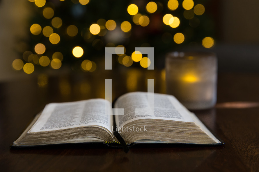open Bible in front of a Christmas tree