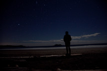 silhouette of a man standing on a beach at night