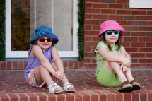 girls in sunglasses sitting on a front porch 