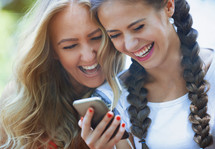 friends smiling looking at a cellphone screen 