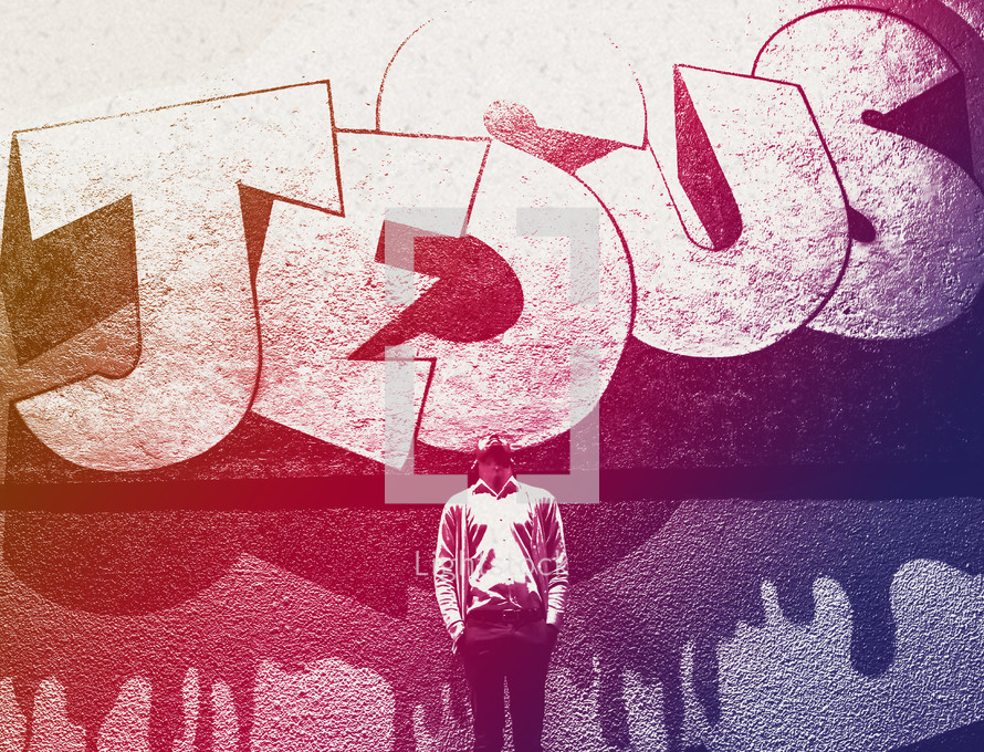 man standing in front of graffiti wall looking up at the word Jesus 
