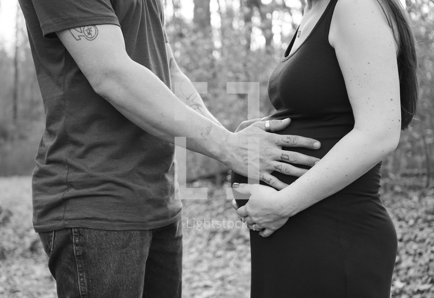 a man and woman with their hands on a pregnant belly 