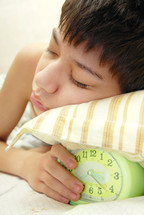 sleepy kid holding an alarm clock 