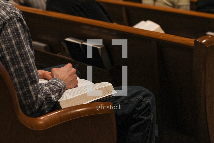 a man sitting in a church pew with a Bible in his lap 