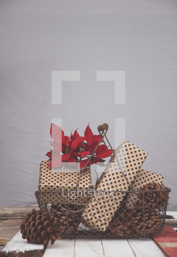 pine cones, presents, and poinsettia in a basket 