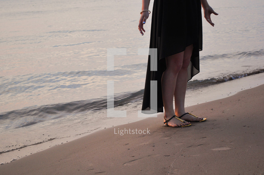 woman in flip-flops standing on the beach 