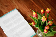 Open Bible and flowers on a wood table 