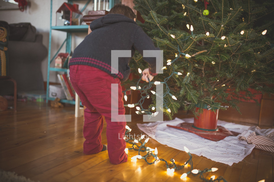 a boy decorating a Christmas tree