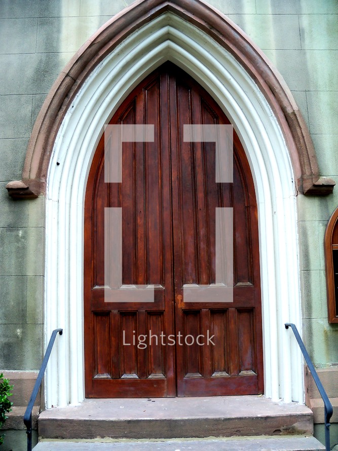 arched wooden doorway entrance to an old historic church in a historic area of downtown. 