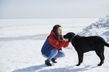 a young woman outdoors in snow with her dog 