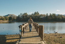 man with long hair walking on a dock