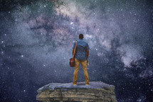 man standing outdoors holding a Bible with stars in the background 