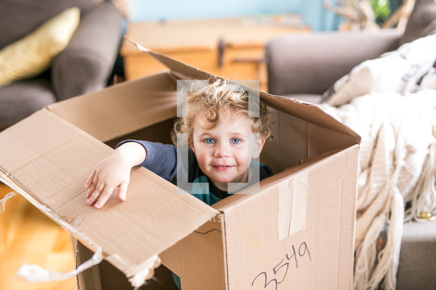 toddler hiding in a cardboard box 
