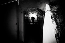 silhouette of a man in a dark tunnel 