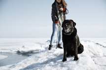 a young woman outdoors in snow with her dog 