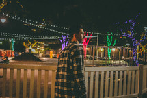 man walking outdoors at night and a Christmas lights display 