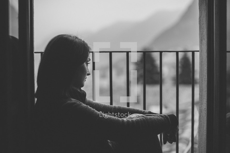 A young woman gazing out a barred window in black and white