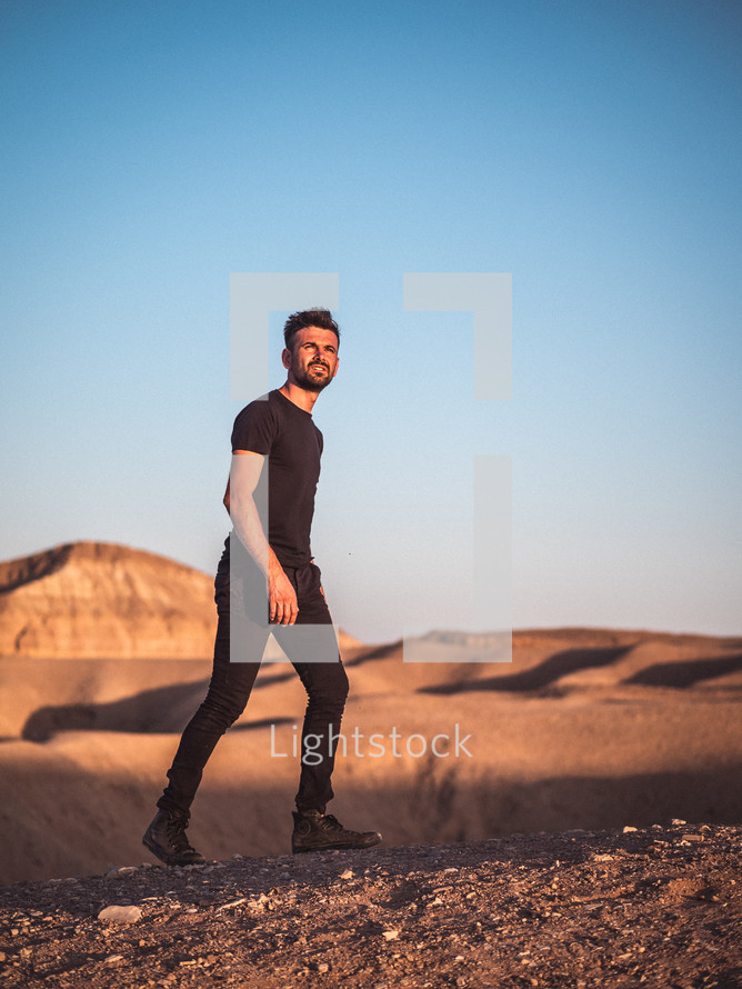 Man in all black walking on dirt