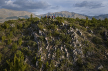 small group of young adults standing on top a ridge with epic mountains behind them