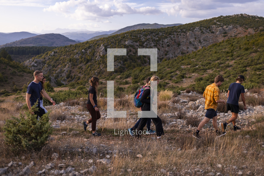 small group of young adults hiking along a ridge in the mountains