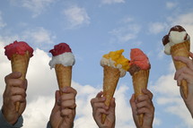 hands holding up ice cream cones 