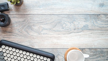 typewriter, coffee mug, camera lens, and houseplant on wood background 
