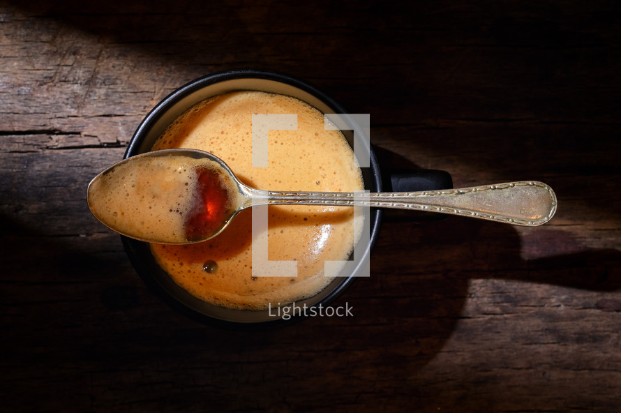 Coffee with foam and a spoon on a wooden table