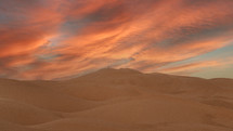 colorful pink clouds over sand dunes 