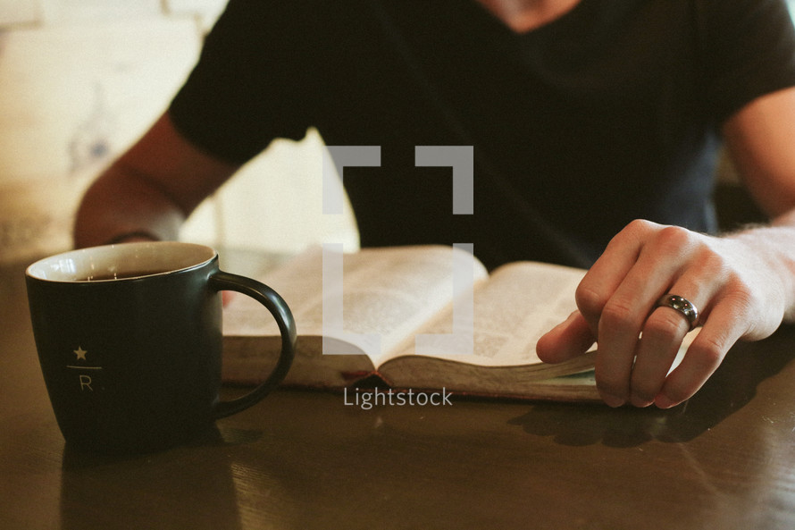 a man reading a Bible with a mug of coffee 