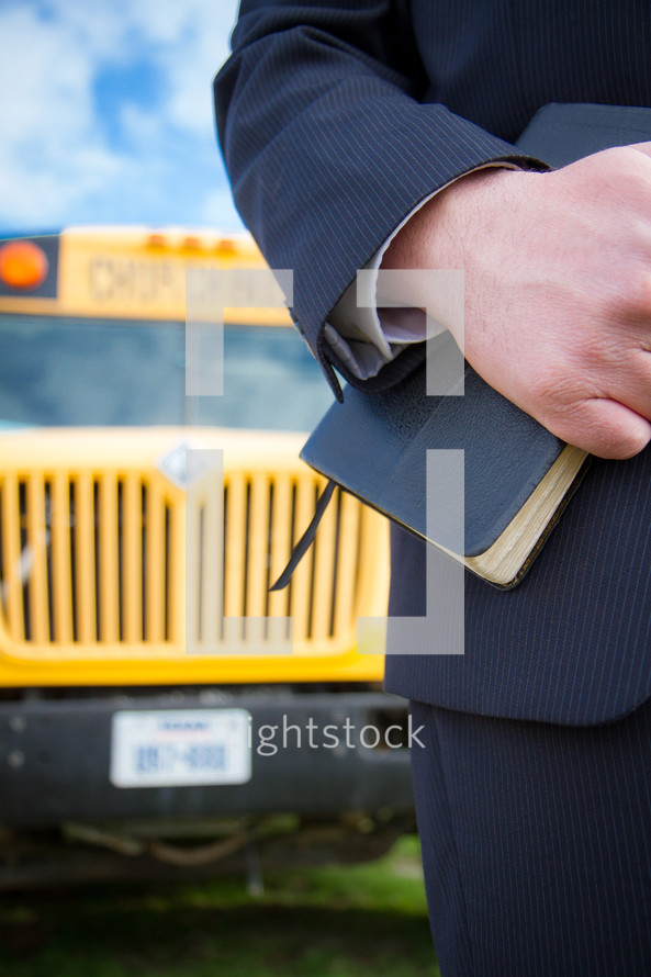man holding a Bible and school bus 