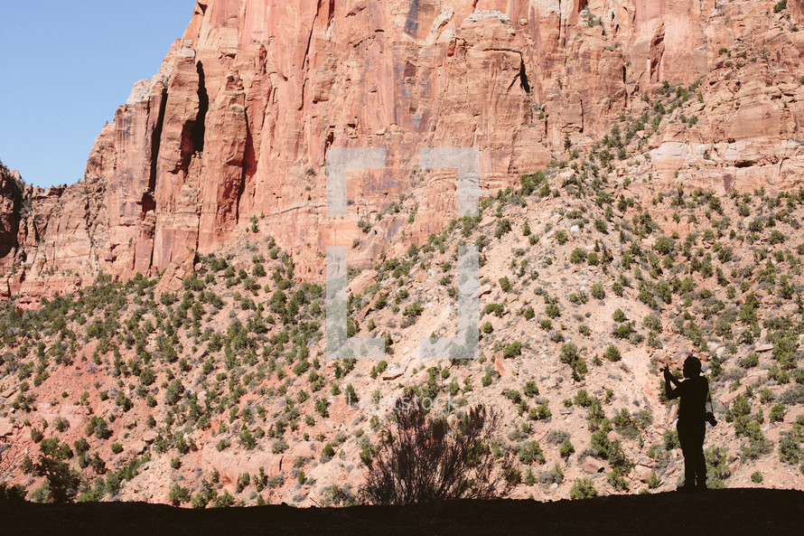silhouette of a man and red rock cliffs 