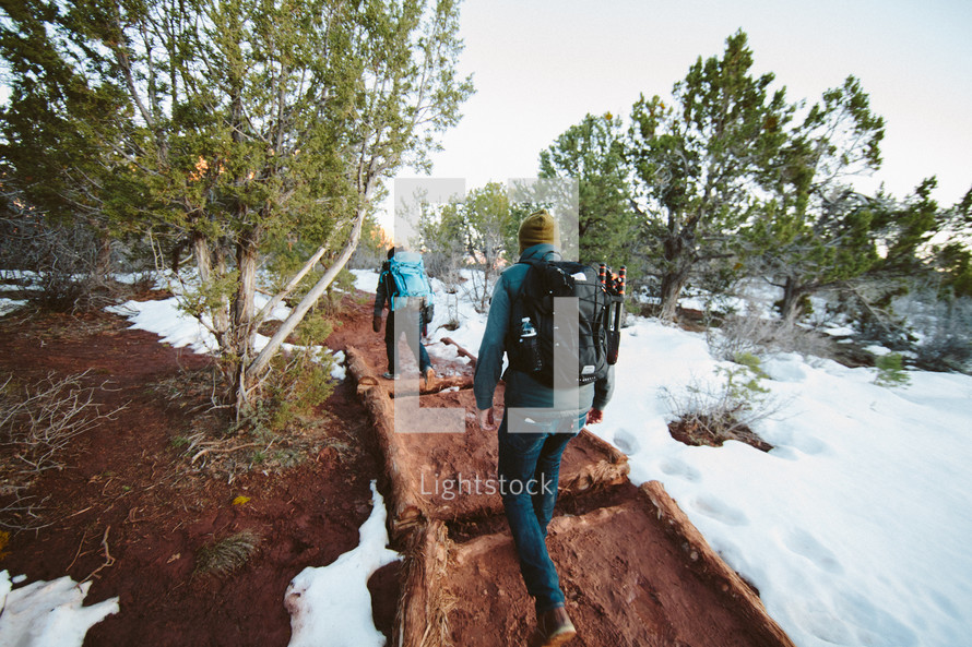 men backpacking on a path through snow 