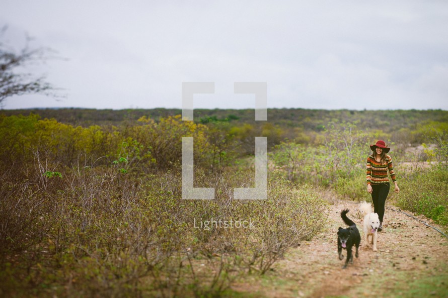 a woman walking on a trail with her dogs 