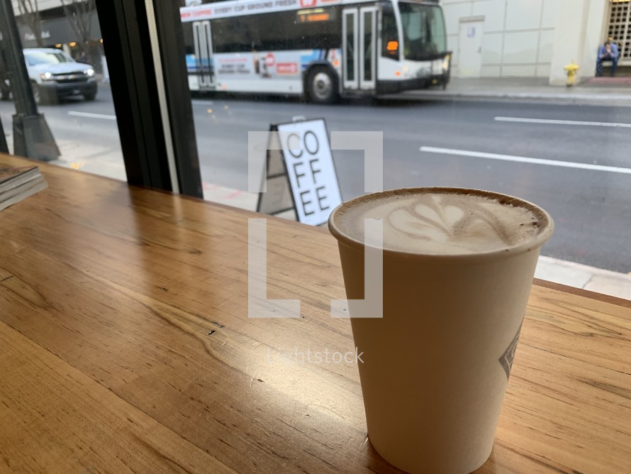 coffee cup on a table and view of a city bus 