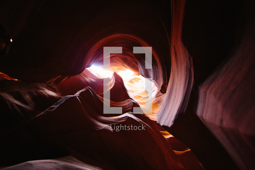 sunlight shining into a red rock cave 