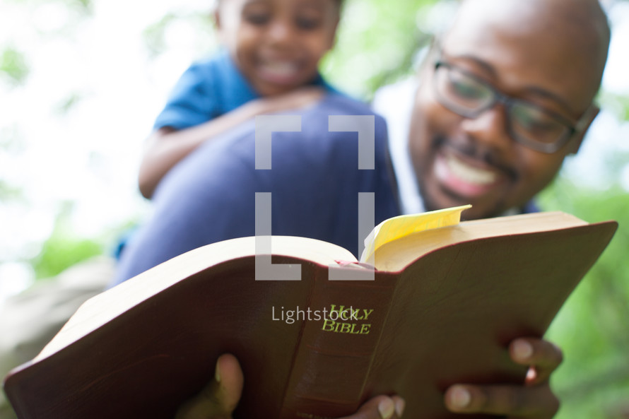 Father and young son reading the Bible.