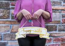 A woman holding a Happy Easter sign 