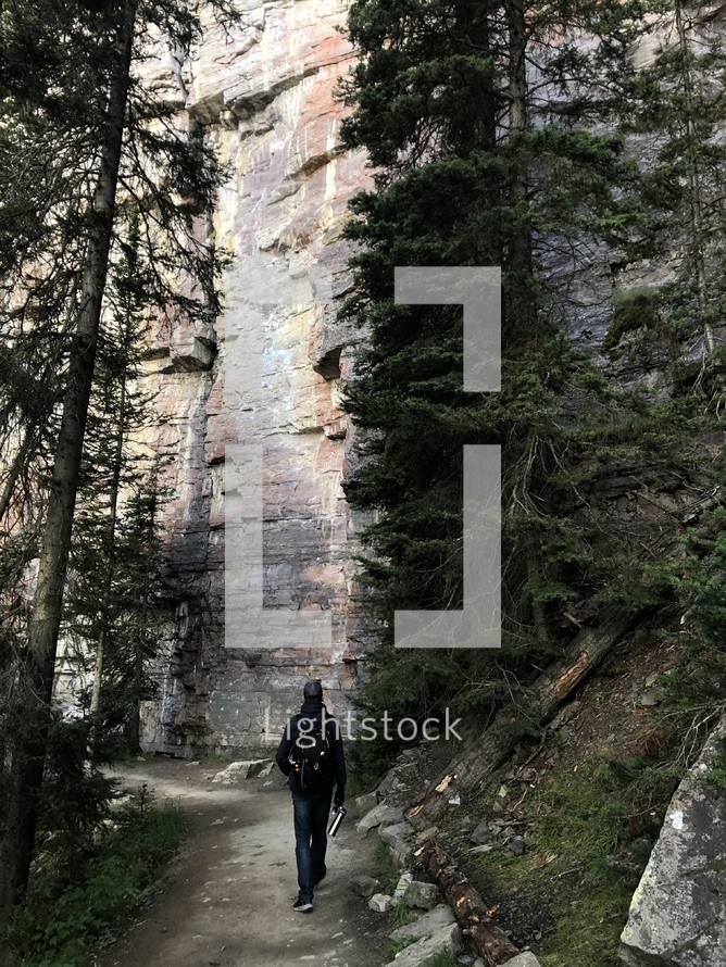 rock cliffs and a man hiking a path 