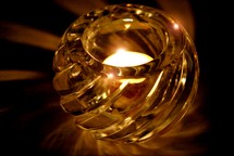 Burning candle in glass votive holder