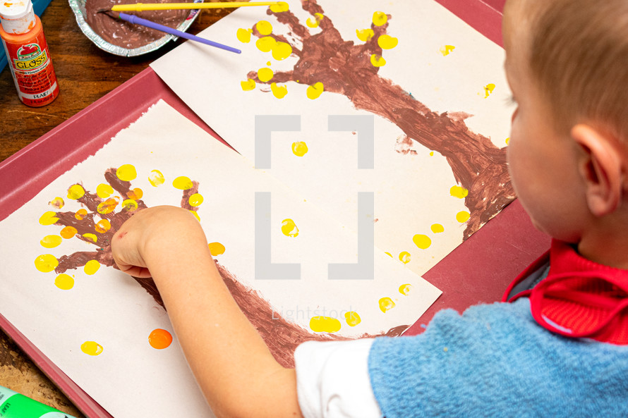 toddler finger-painting an autumn tree