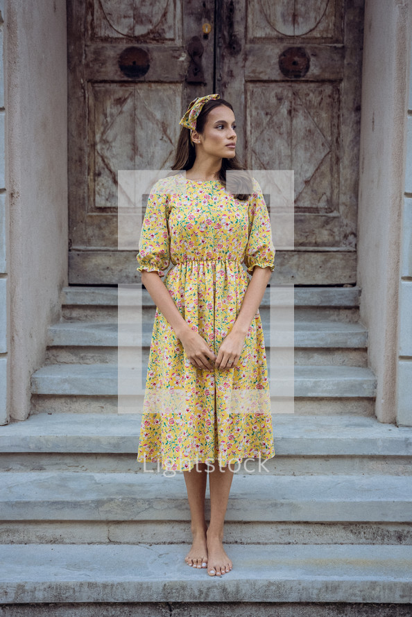 Woman in floral dress in front of old doors
